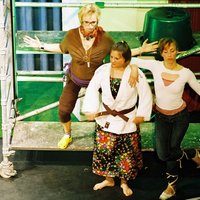 Drei Spielerinnen stehen auf einer Bühne an einem Baugerüst