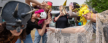 Sechs Personen mit selbst gestalteten Masken vor dem Gebäude der Fachschulen