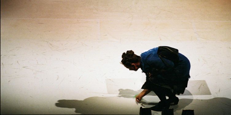 Schauspielerin wischt den Boden einer Theaterbühne