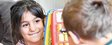 Zwei Kinder spielen ein Spiel, das Gesicht eines lachenden Mädchens und ein Kind von der Seite.