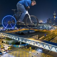 Stadt bei Nacht, Mann auf Fahrrad über die Stadt in blau, Hinterrad ist ein Riesenrad