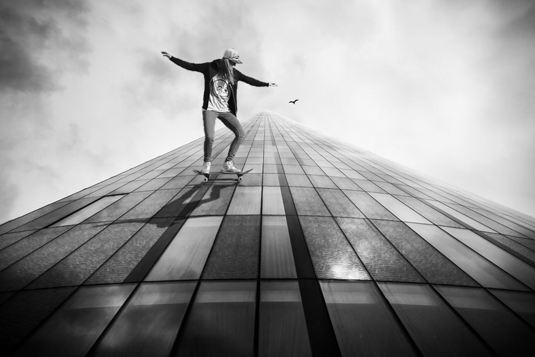 Skaterin an einem Hochhaus, das in die Wolken strebt, ein Wolkenkratzer.